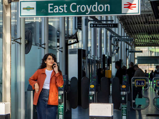 A woman is standing under a sign that says East Croydon.