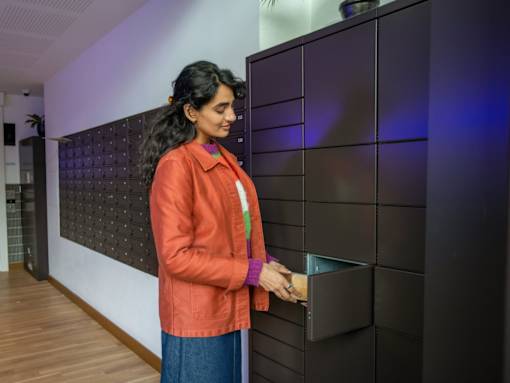 A woman in an orange jacket is opening a black box.