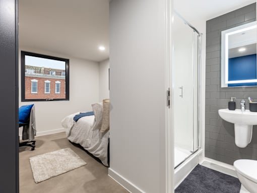A bedroom with a bed, a chair, and a window.