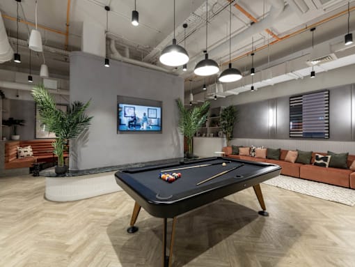 A pool table is in the middle of a room with a TV on the wall.