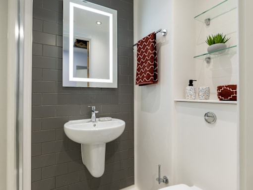A white sink is mounted on a grey wall under a mirror.