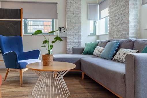 A living room with a grey couch, a blue chair, and a wooden table.