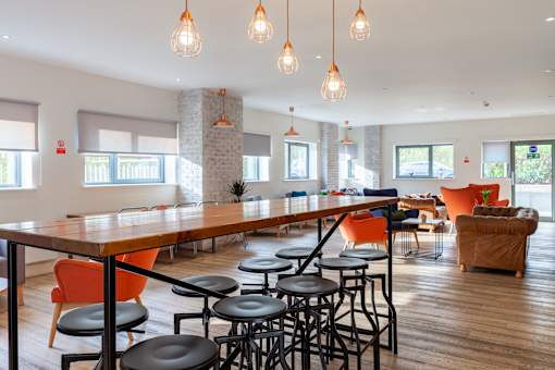 A modern dining area with a long table and orange chairs.