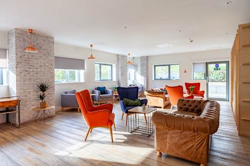 A living room with a variety of chairs and a stone fireplace.