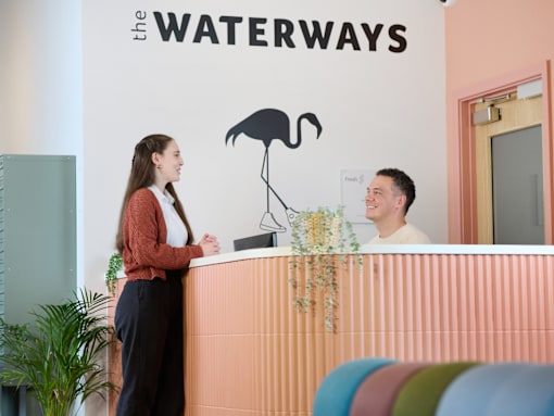 A woman is standing at the front desk of the Waterways.