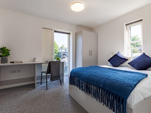 A bedroom with a bed, desk, and chair.