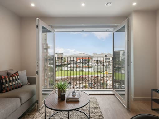 A living room with a couch, a table, and a view of the city through the sliding glass doors.