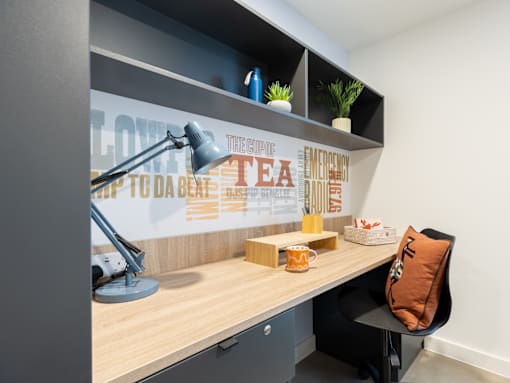 A desk with a lamp and a cushion on it.