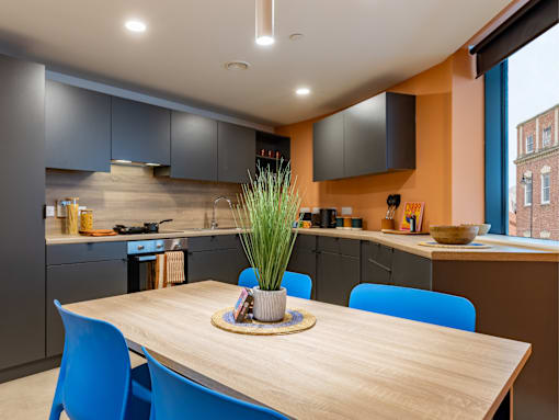 A modern kitchen with a wooden table and blue chairs.