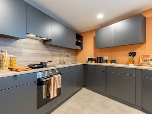 A kitchen with grey cabinets and a black oven.