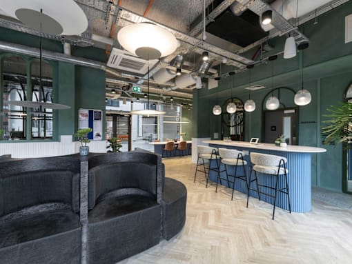 A modern office space with a black couch and a bar area.