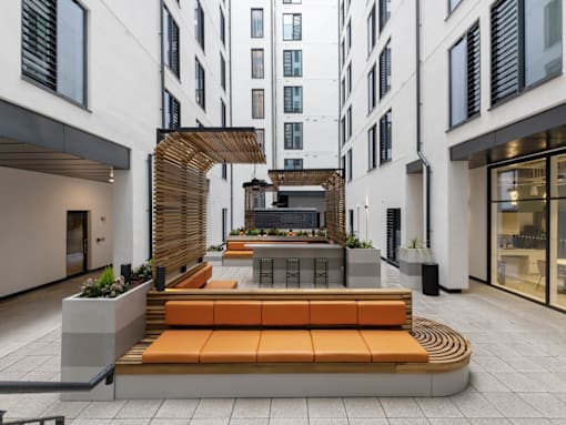 A modern courtyard with a wooden spiral staircase and orange seating.