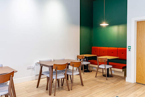 A room with a green wall and a wooden table with chairs.
