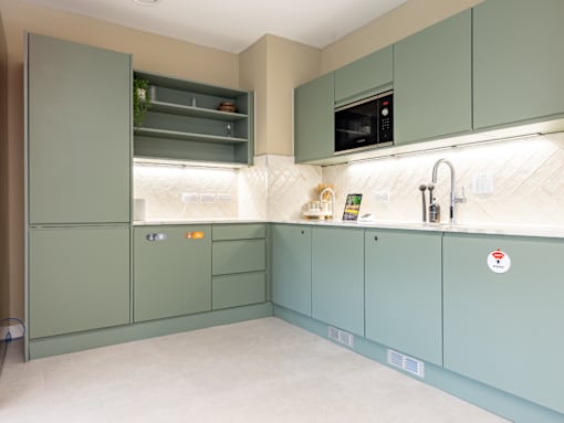 A kitchen with green cabinets and a white countertop.