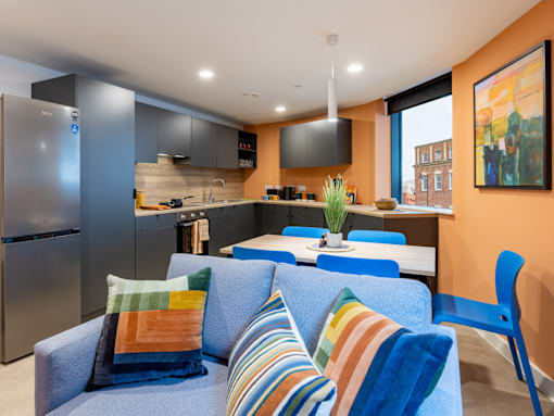 A modern kitchen with a blue couch and striped pillows.