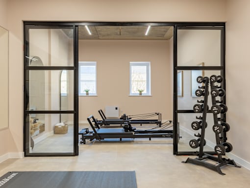 A gym with a row of dumbbells on the right and a row of bench presses on the left.