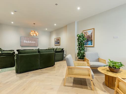 A room with a couch, chairs, and a table with a plant on it.