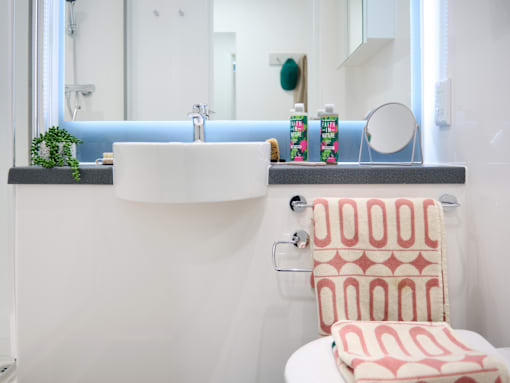 A white sink with a red and white towel on a white toilet.