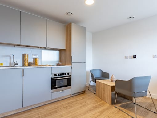 A modern kitchen with a wooden floor and white walls.