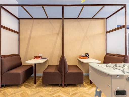 A room with brown chairs and a white table with a glass partition.