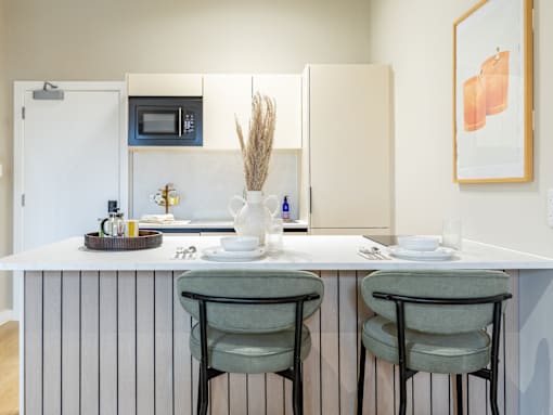 A kitchen with a white counter and two green chairs.