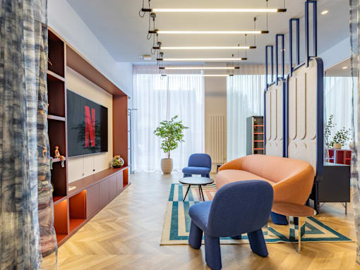 A modern living room with a blue chair and a TV on the wall.