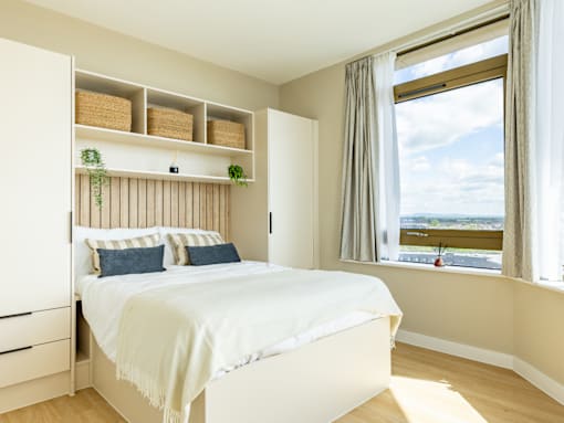 A bedroom with a bed, nightstand, and window.