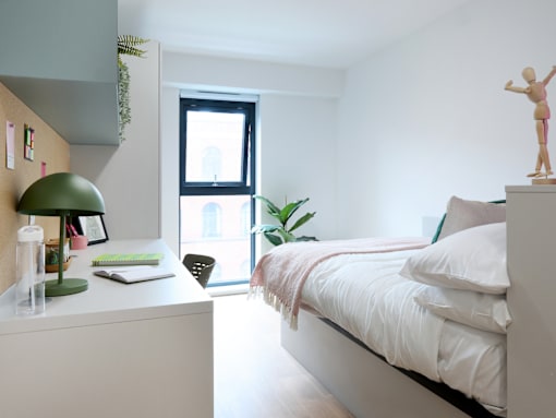 A bedroom with a bed, desk, and window.