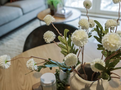 A vase with white flowers sits on a wooden table.