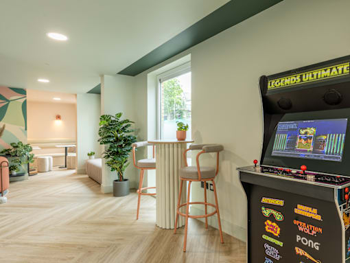 A room with a Legends Ultimate pinball machine on a stand.