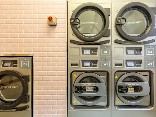 Three washing machines are lined up against a brick wall.