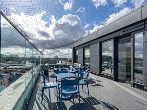 A balcony with a table and chairs overlooking a cityscape.