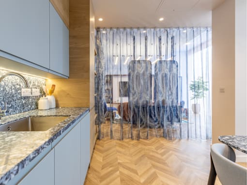 A kitchen with a marble countertop and wooden flooring.