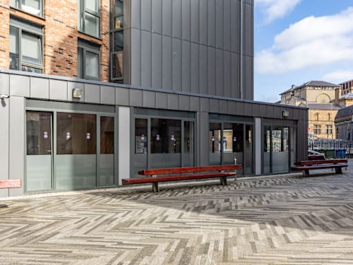 A modern building with a glass entrance and a bench in front.