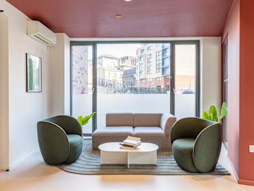 A living room with a grey sofa, two green chairs and a white coffee table.