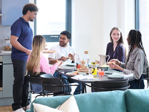 A group of people are gathered around a table eating food.