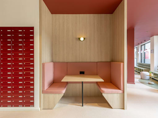 A wooden table with a bench in front of a wall with red drawers.