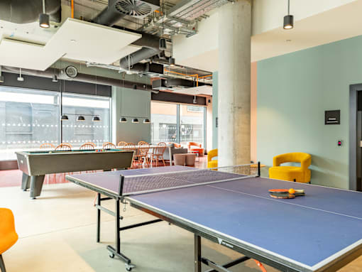 A ping pong table is in the middle of a room with chairs around it.