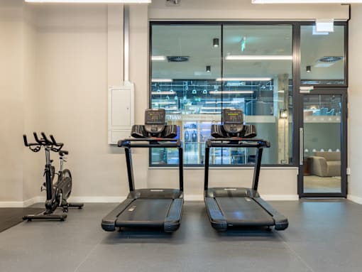 Two treadmills and a stationary bike in a room.