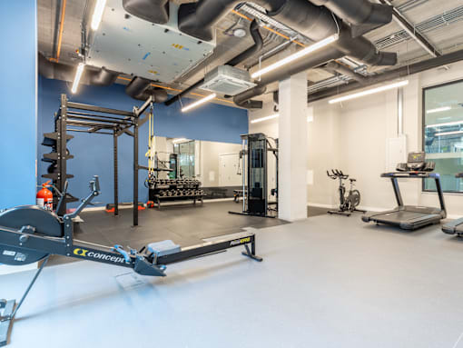 A gym with a rowing machine in the foreground.