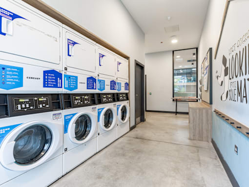 A row of washing machines are lined up in a laundromat.