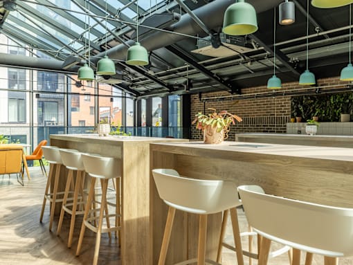 A modern bar with white chairs and a wooden counter.