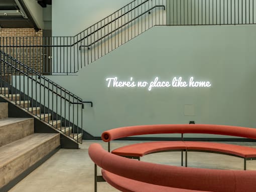 A staircase with a metal railing and a red bench.