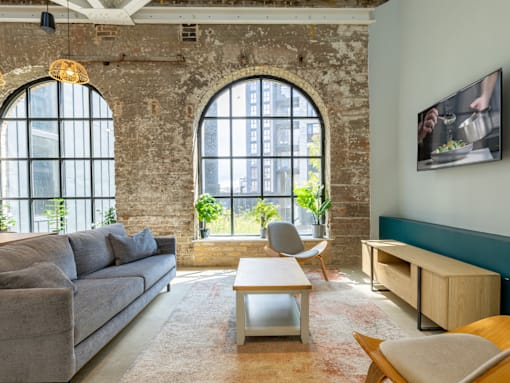 A living room with a grey couch, a wooden table, and a large window.