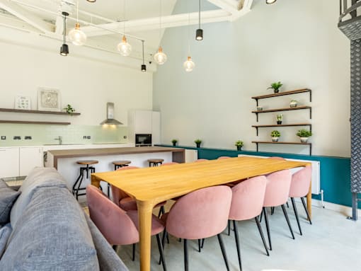 A modern dining area with a wooden table and pink chairs.