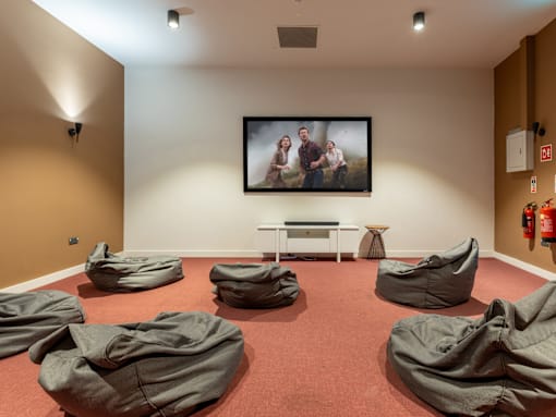 A room with bean bag chairs and a painting of three people on the wall.
