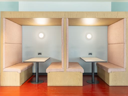 Two booths with tables and chairs in a room.