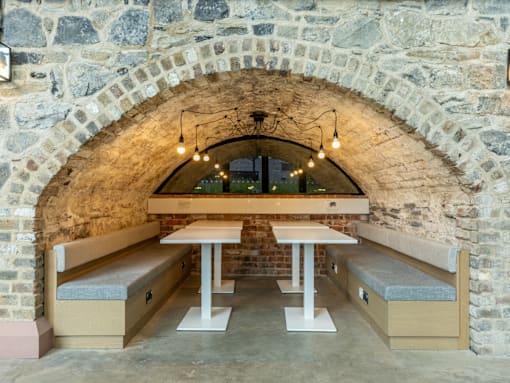 A stone archway with a table and benches under string lights.