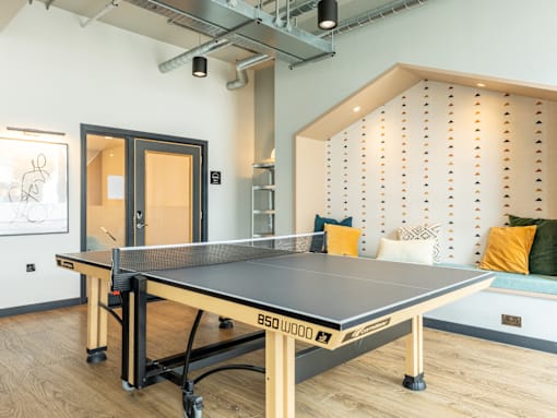 A ping pong table is in the middle of a room with a white wall and a black door.