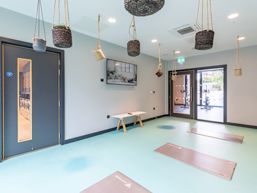 A yoga studio with a blue floor and hanging baskets.